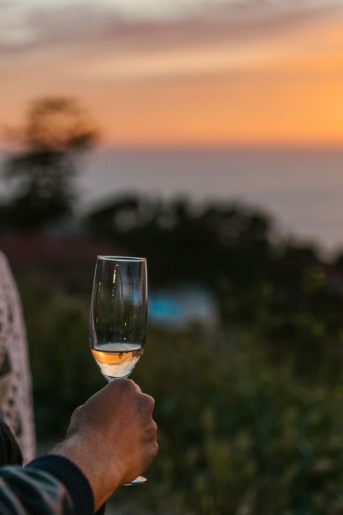 Free A close-up of a champagne glass being held outdoors during sunset. Stock Photo
