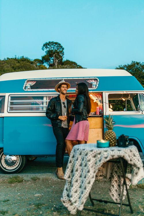 Free A joyful couple standing by their retro camper van, enjoying a summer road trip outdoors. Stock Photo