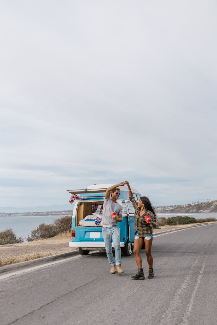 Couple Standing On Road Near Blue Van