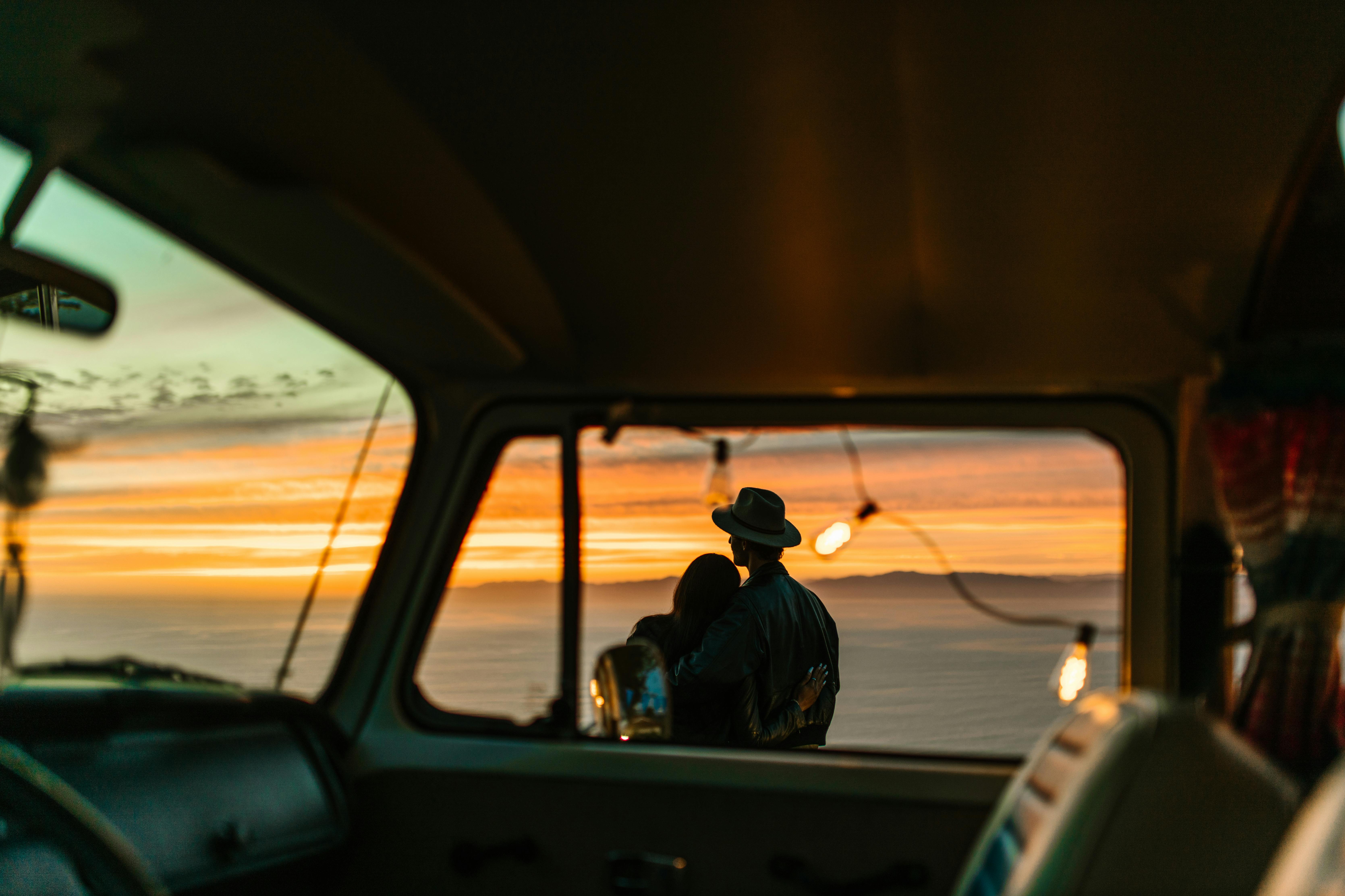 a couple hugging near a vehicle at sunset