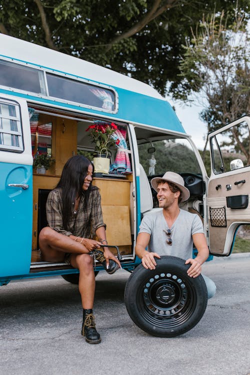 A Man Holding a Space Tire While a Woman sitting in the Van