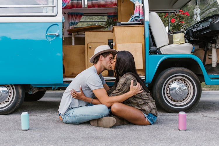 A Couple Kissing While Sitting On The Concrete Road Near The Van