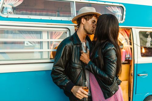 Free A couple sharing a romantic kiss outside a vintage blue van, embodying love and adventure. Stock Photo