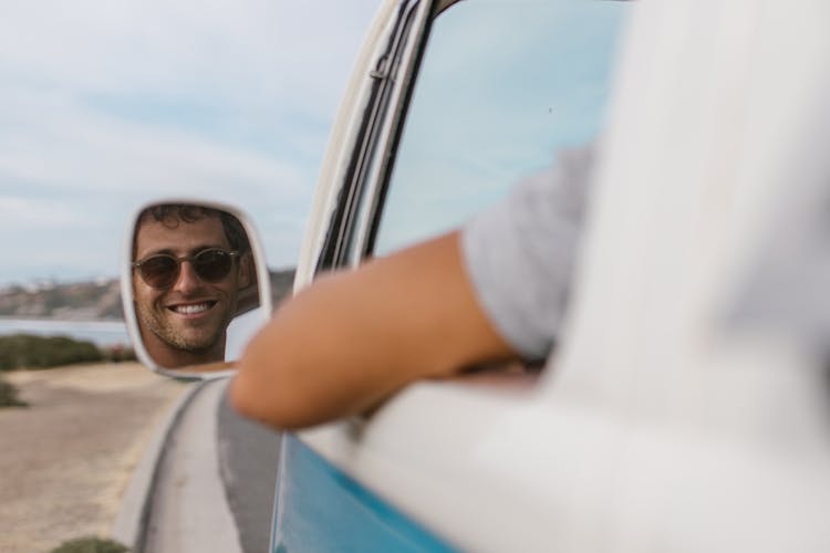 Reflection Of A Man Wearing Sunglasses On The Side Mirror Of The Van