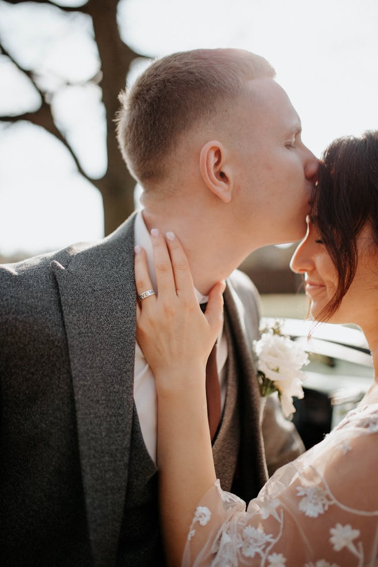 A Man Kissing A Woman In Forehead