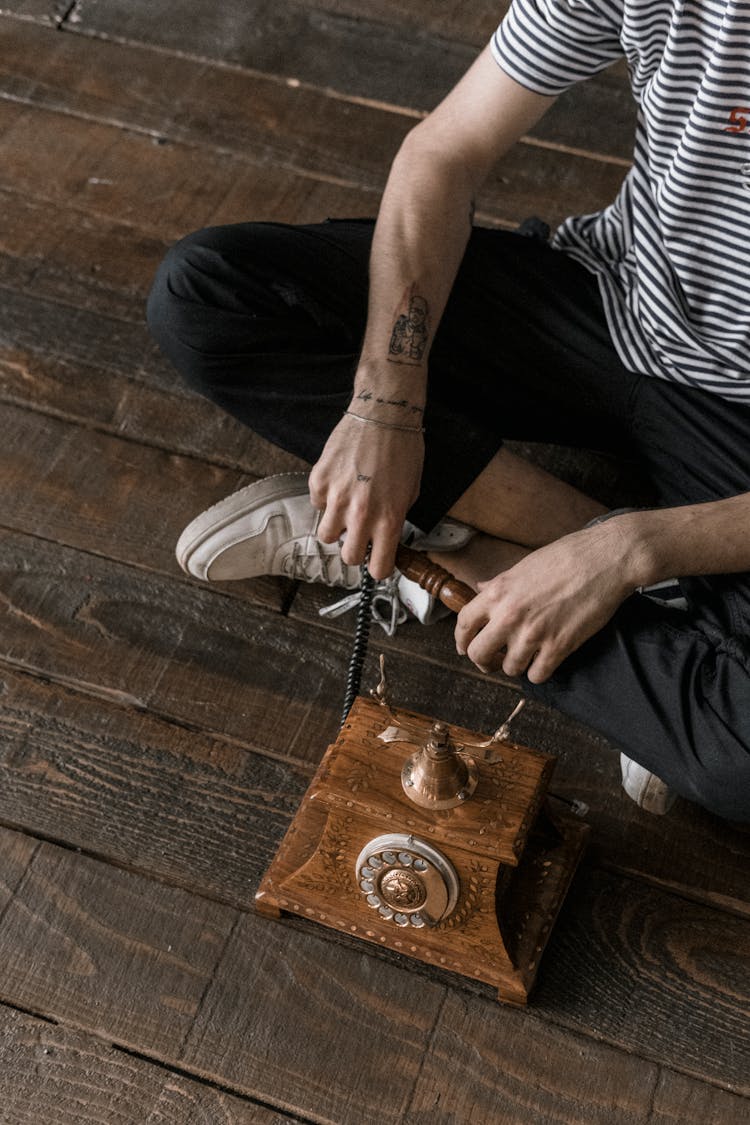 Crop Man Sitting On Wooden Floor