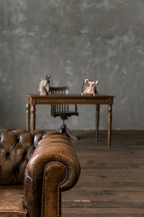 Free A classic styled room featuring a vintage leather sofa and a wooden desk with retro decor, exuding a timeless charm. Stock Photo