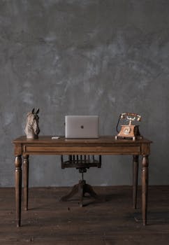 Elegant vintage desk featuring a modern laptop and antique rotary phone, ideal for office inspiration.