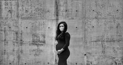 Pregnant Woman standing in Front of Concrete Wall