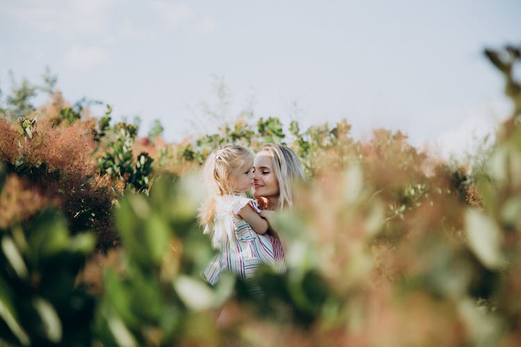 Mother And Lovely Daughter Surrounded By Garden Plants