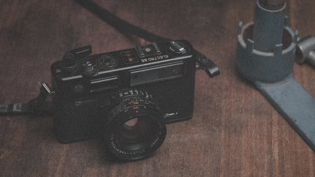 Close-up of a classic vintage camera with lens and viewfinder on a wooden table.