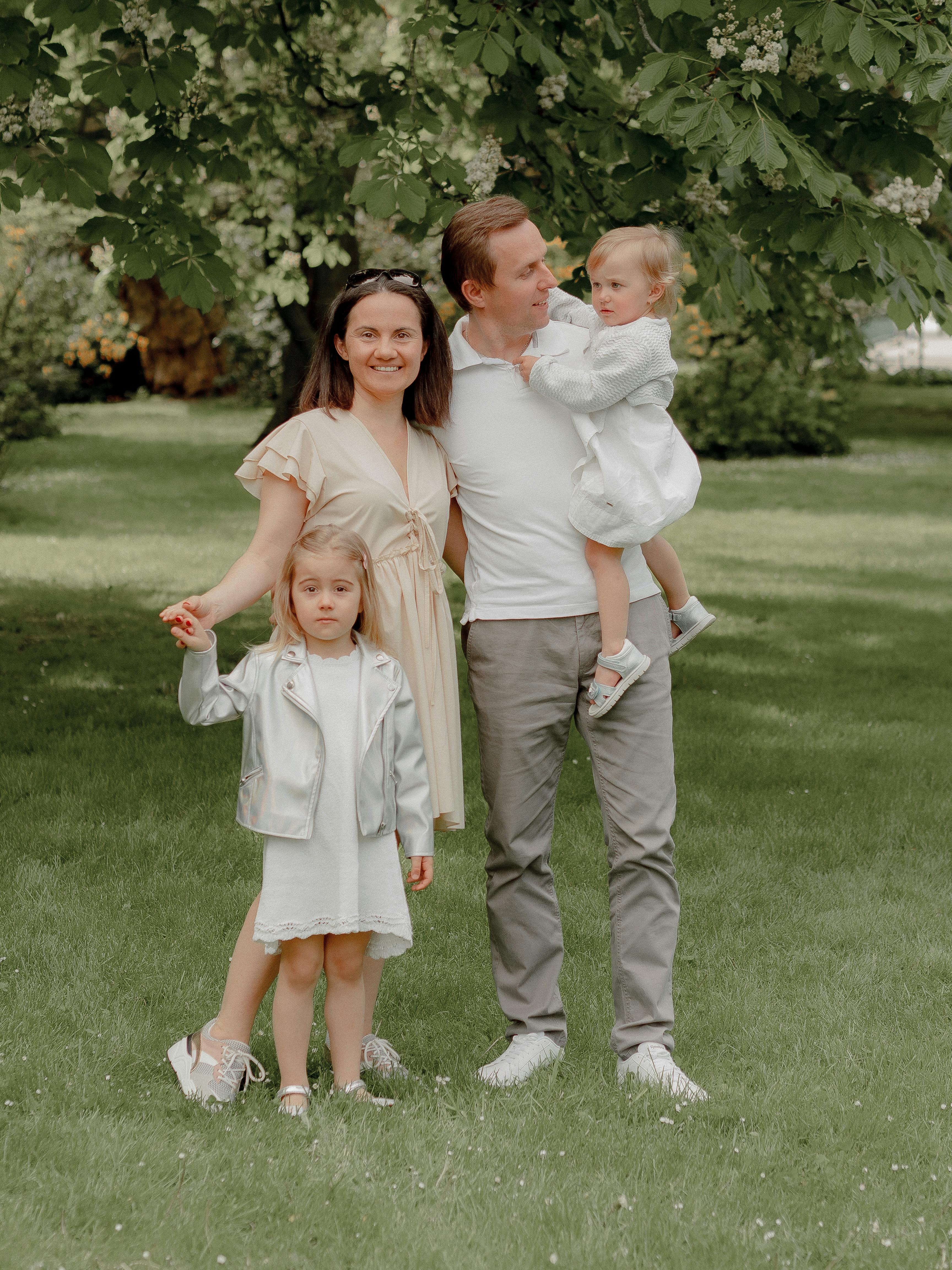 portrait of a family dressed bright in a garden with blossoming chestnut tree