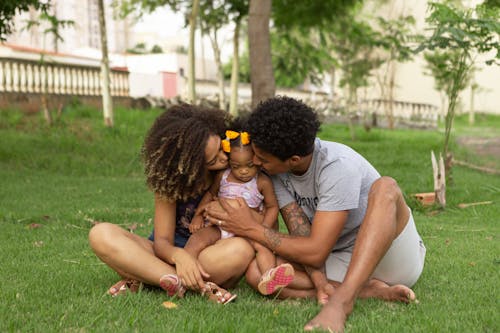 Free Dad and Mom Kissing Their Baby Girl Stock Photo