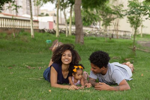 Free Mother, father, and daughter bonding on green grass in a park, enjoying quality family time. Stock Photo