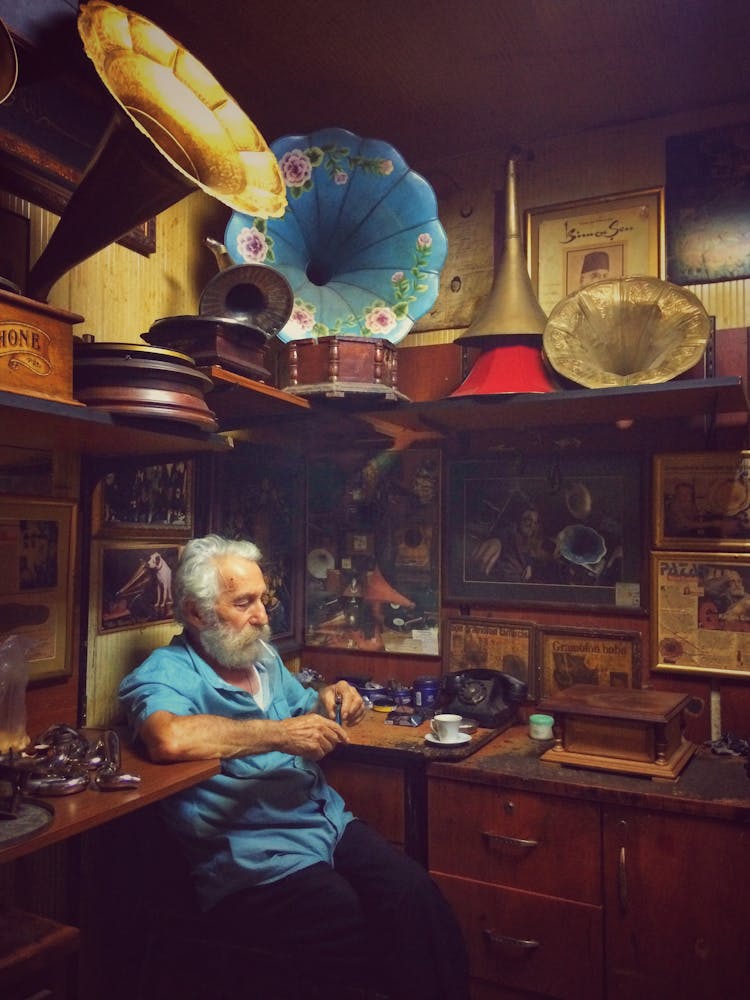 Gramophone Collector Sitting In Room With Old Music Equipment 