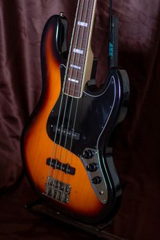 Detailed view of an electric bass guitar with a brown background, highlighting its strings and body.