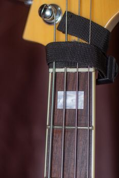 Detailed view of guitar headstock, showing frets and string muter for clean sound.