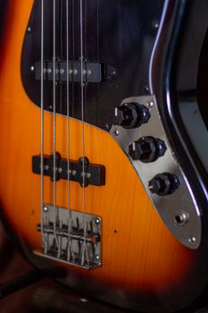 Detailed view of a bass guitar focusing on strings and control knobs.