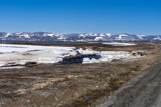 Idyllic winter scene featuring snowy hills and a winding stream in Jämtlands län, Sweden.