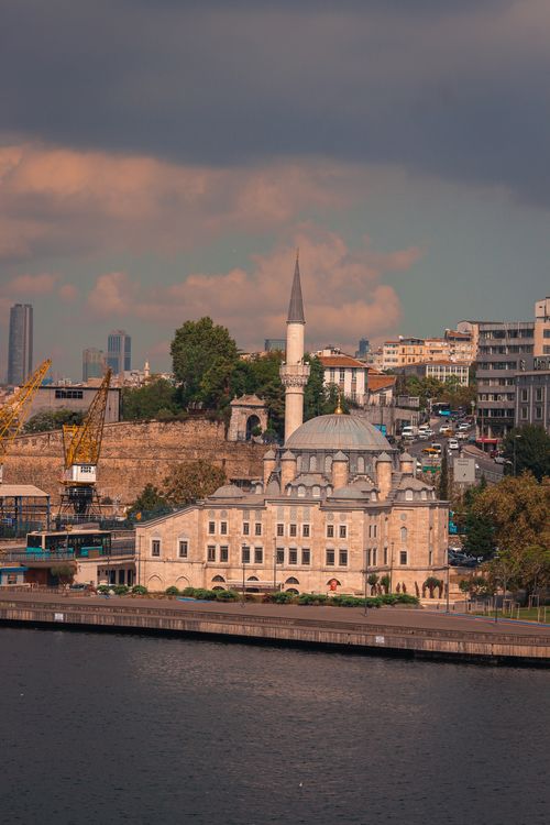Free A beautiful view of a mosque by the canal in Istanbul, Türkiye during twilight with dramatic clouds. Stock Photo