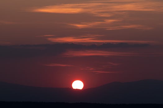 Captivating sunset with a dramatic sky casting a silhouette over distant mountains.