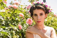 阳光明媚的花园里，玫瑰盛开，一幅戴着花冠的女人的肖像