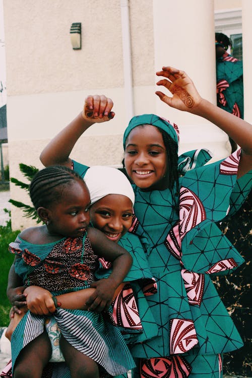 Smiling black sisters in colorful clothes having fun together