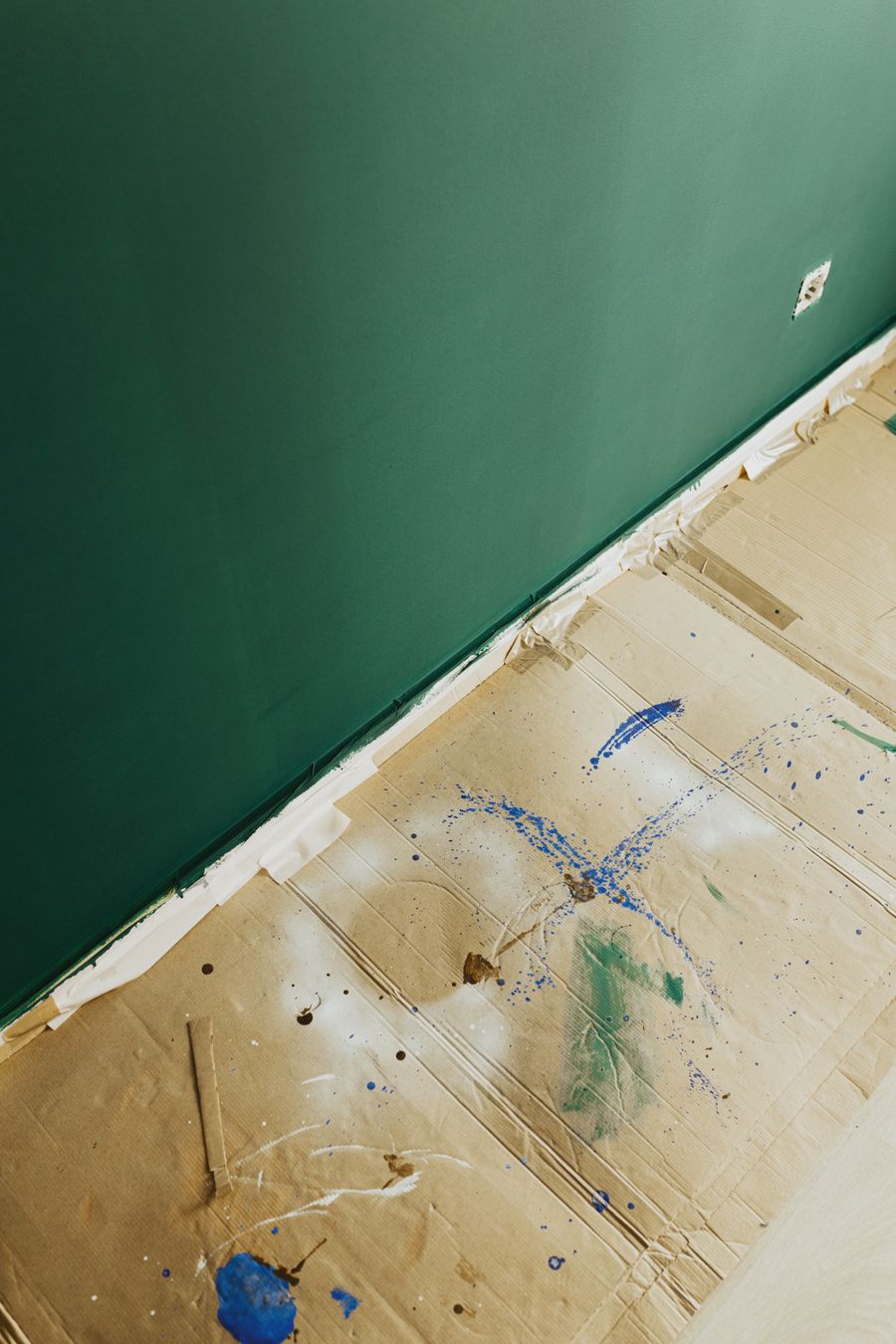 Freshly painted green wall with cardboard protecting the floor