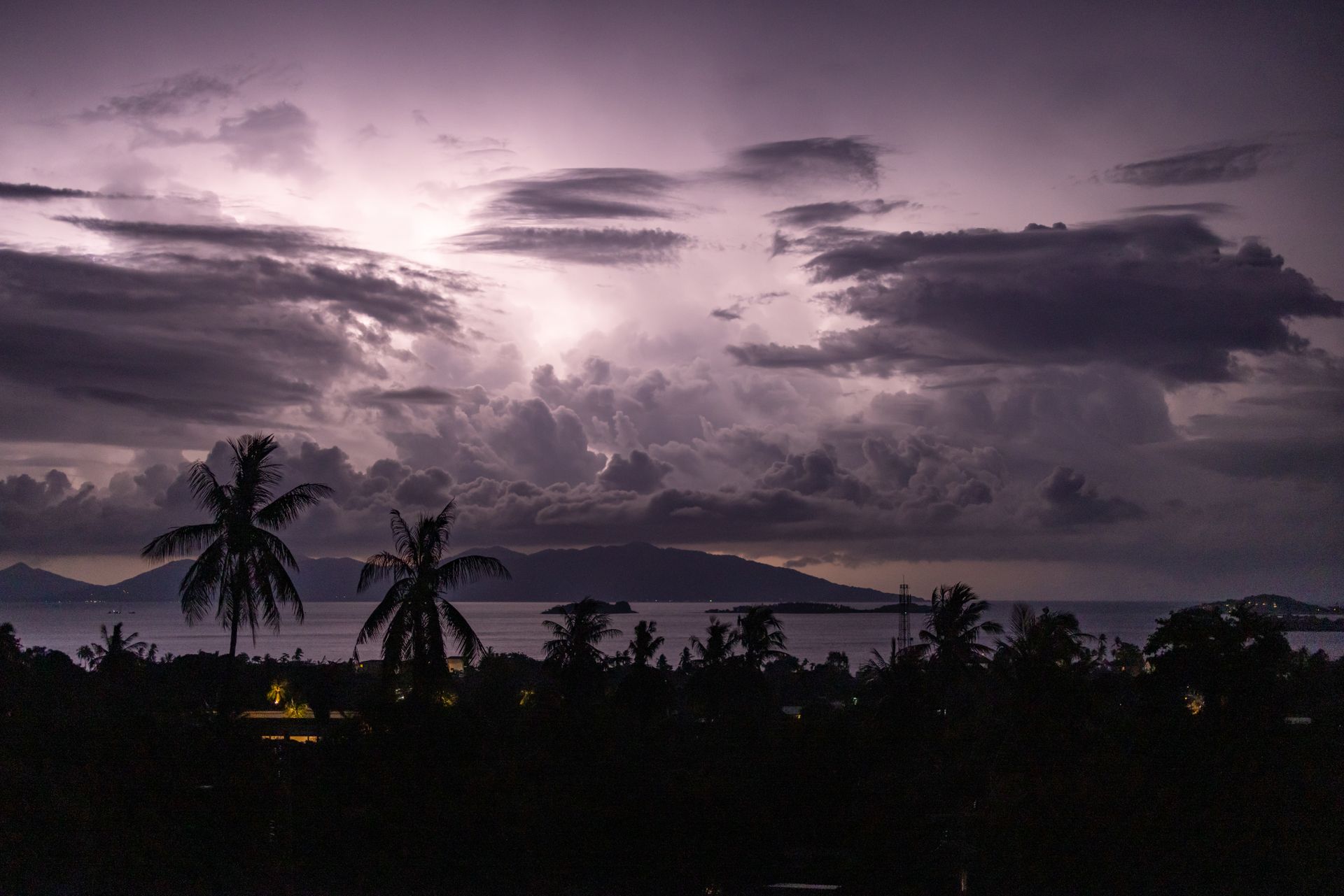 A dramatic tropical storm sky with cloud formations over the ocean at night.