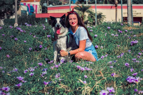 Woman in a White Shirt Sitting Beside a Black and White Border Collie
