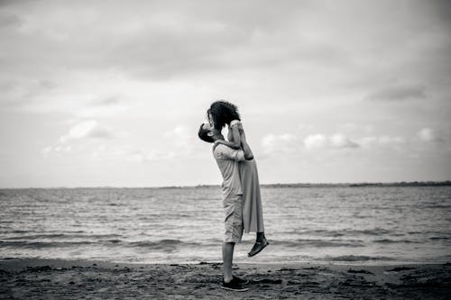 Monochrome Photo of a Man Lifting a Woman at the Beach