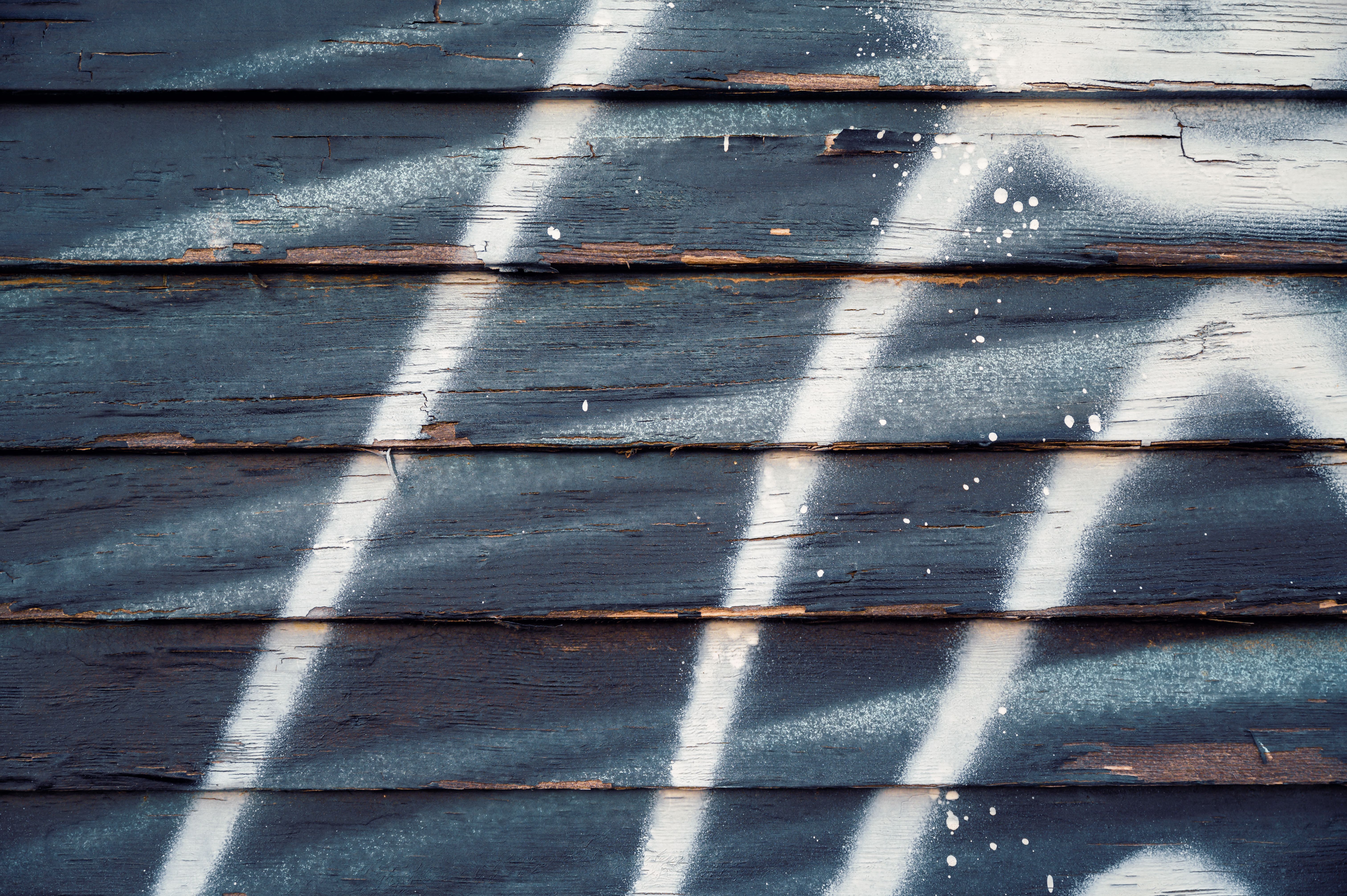 Close-up of peeling wooden planks with abstract graffiti texture in white and black.