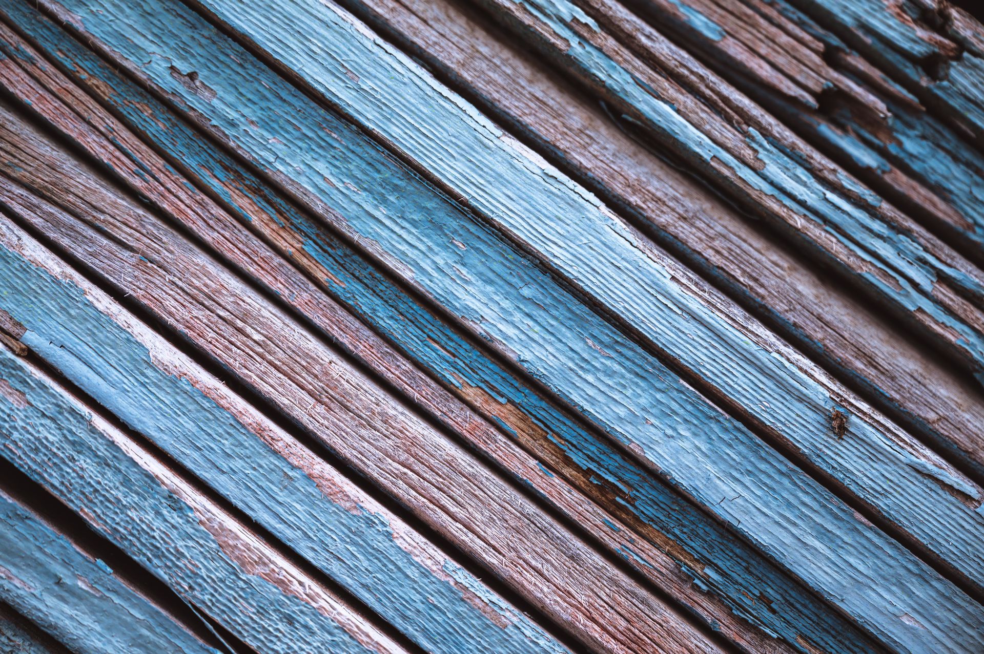 Detailed texture of aged blue wooden panels with peeling paint.