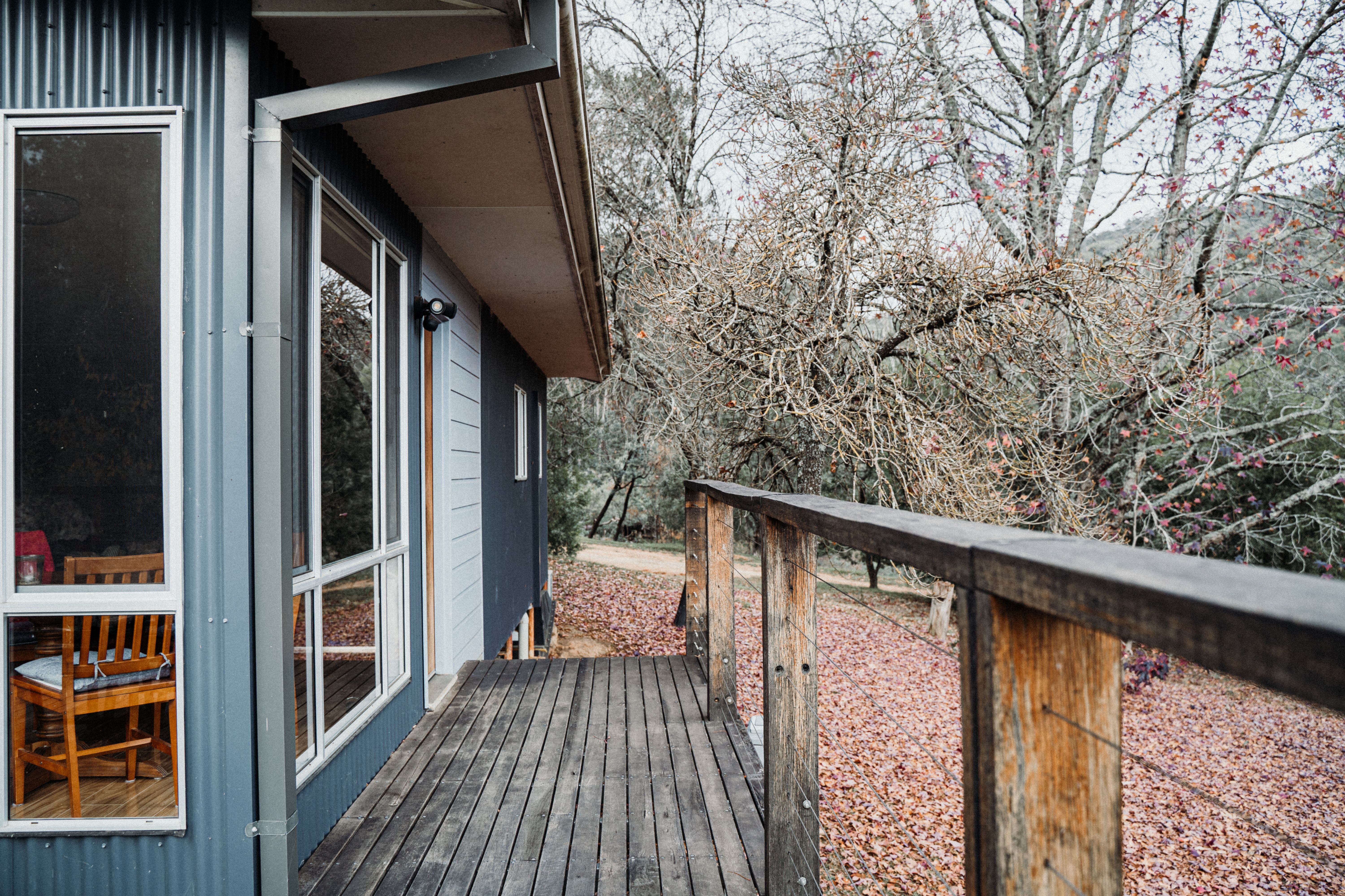 Cozy country house with wooden deck amidst autumn leafless trees.