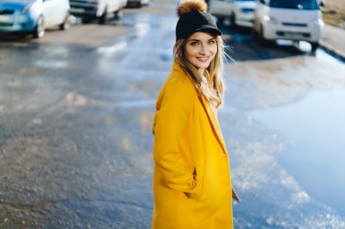 Selective Focus Photo of a Woman Wearing a Yellow Coat and a Black Cap