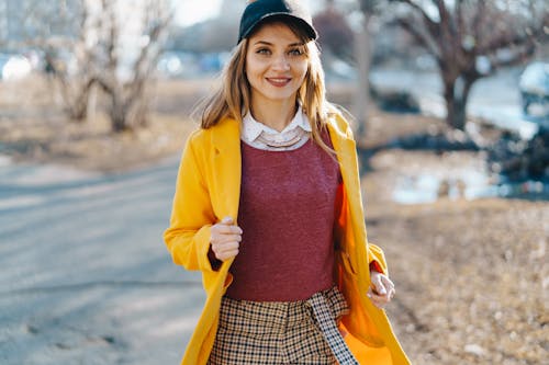 Free A Woman Smiling while Wearing a Yellow Coat Stock Photo