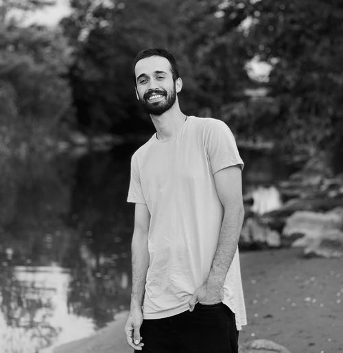 Free Portrait of a smiling bearded man standing outdoors in a serene natural setting. Stock Photo
