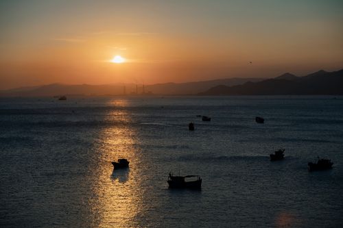 Free Boats silhouetted against a serene ocean sunset, capturing a tranquil evening view. Stock Photo