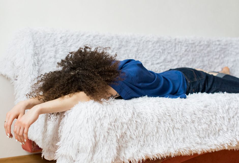 Woman sitting on couch making excuses not to exercise