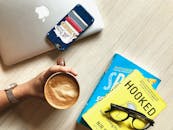 工作空间的俯视图显示，木制桌子上有书籍、咖啡和智能手机