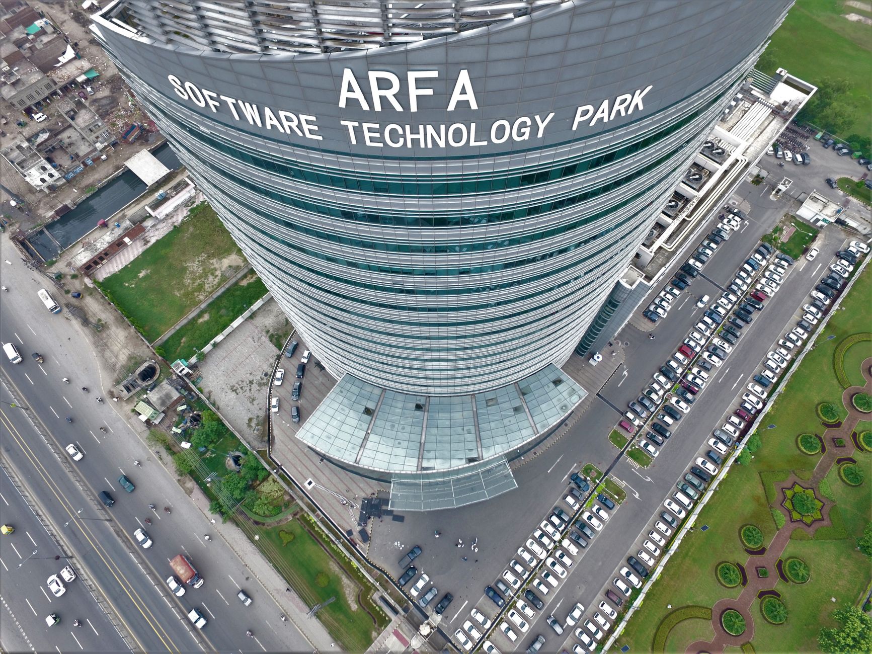 Drone shot of Arfa Software Technology Park skyscraper with cars and road below.