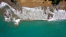 航拍镜头捕捉到海浪拍打哥斯达黎加郁郁葱葱的岩石海滩，景象令人惊叹