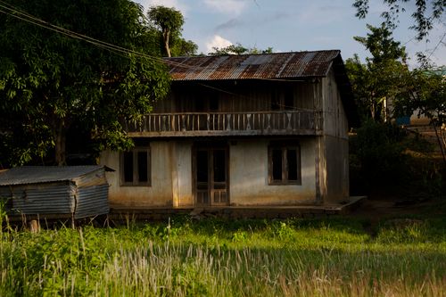Free Abandoned wooden house in a lush field surrounded by greenery during daytime. Stock Photo
