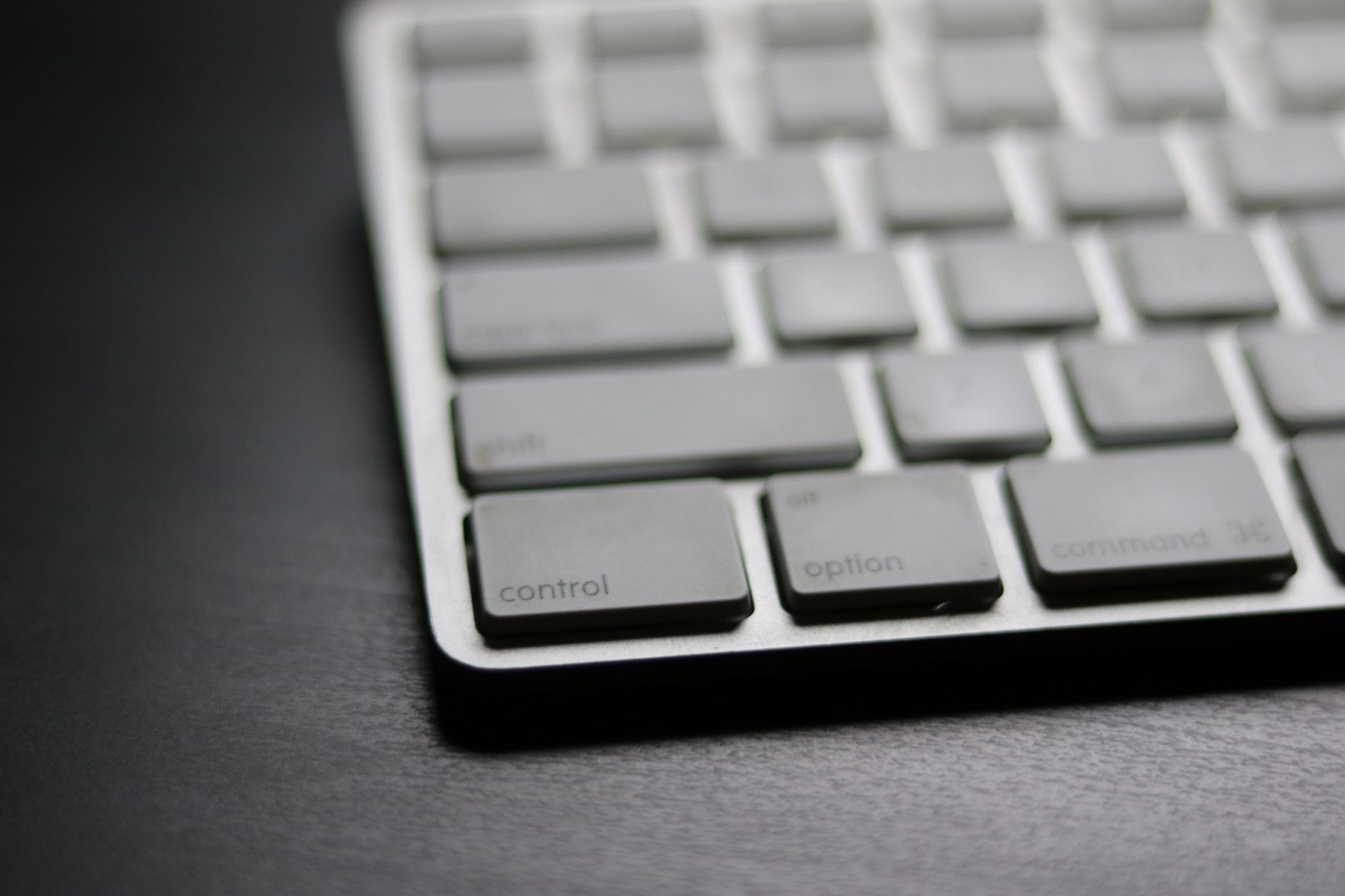 Detailed close-up of a sleek modern wireless keyboard on a dark surface.
