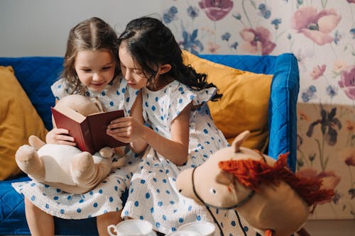 Free Girls in Same Polka Dots Dress Reading a Book Stock Photo