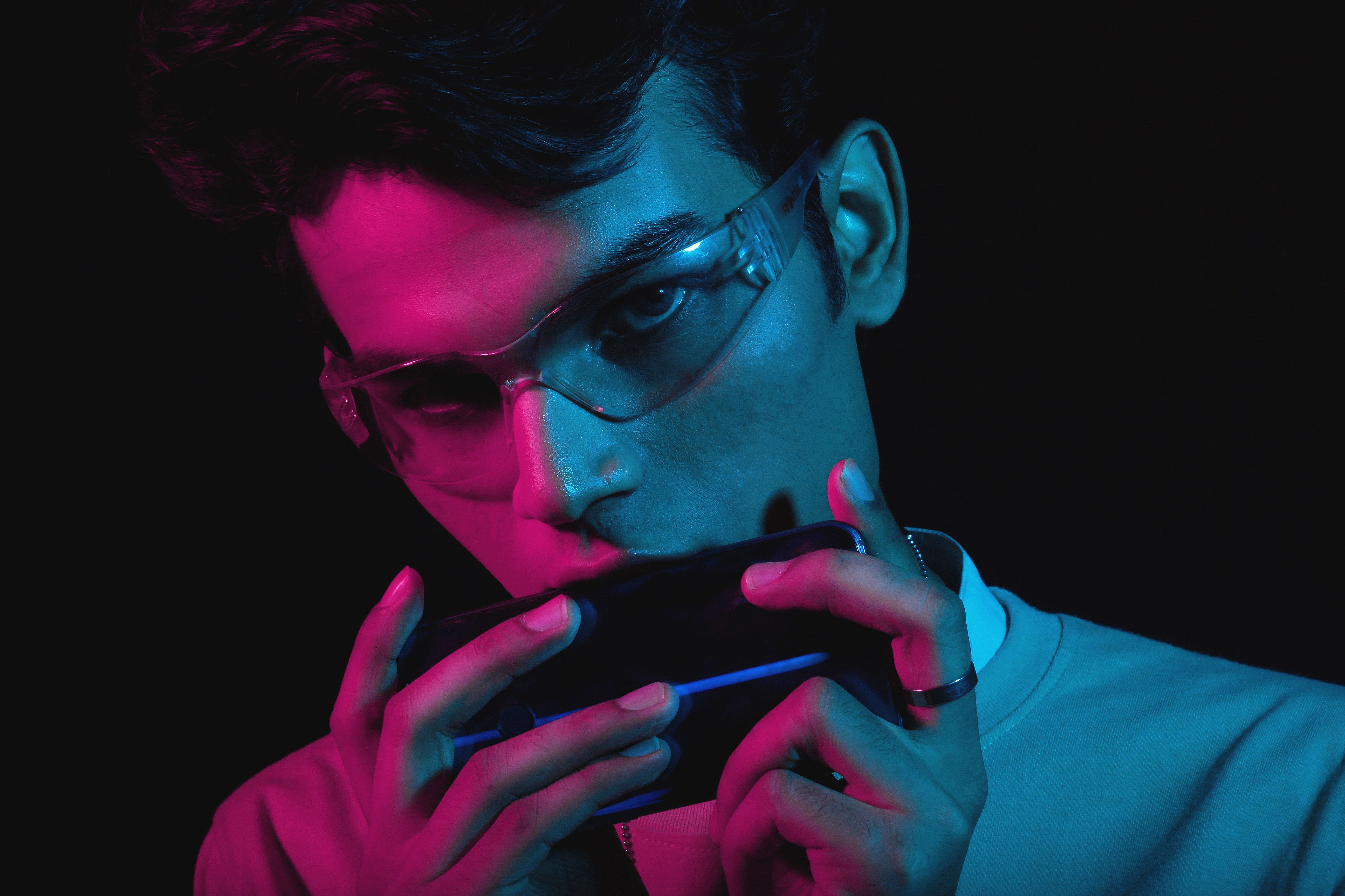 Close-up portrait of a man with sunglasses in vibrant neon lighting.