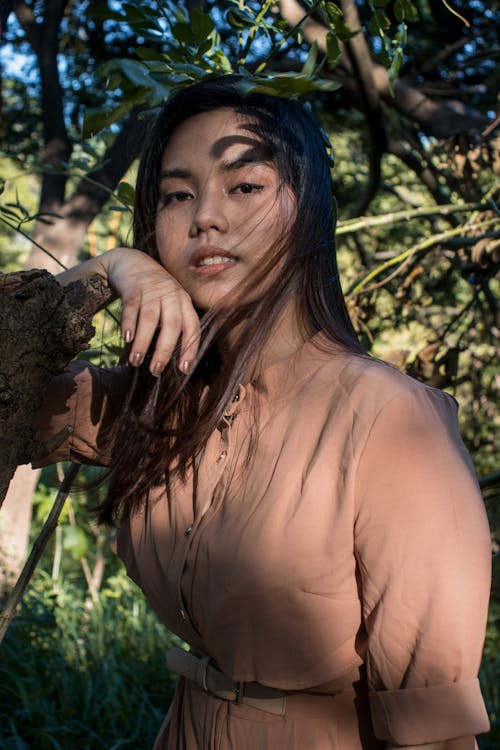 Woman Wearing Brown Dress Leaning on a Tree 