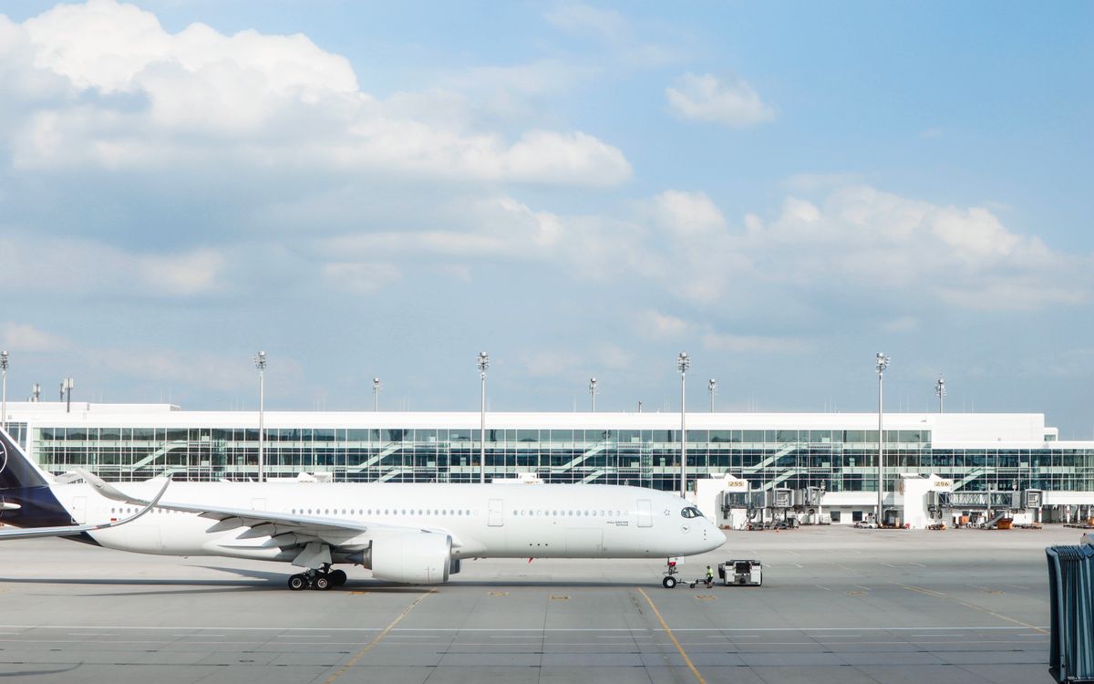 Widebody aircraft parked at an airport gate during clear day with terminal building visible.