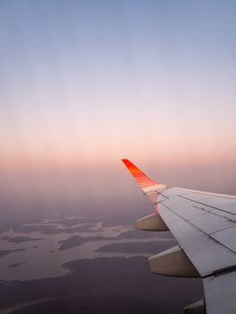 View from airplane window showing wing and serene sunset over landscape.