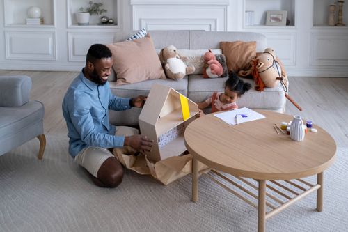 Free A father and daughter bond over a creative play session with a dollhouse in a cozy living room. Stock Photo